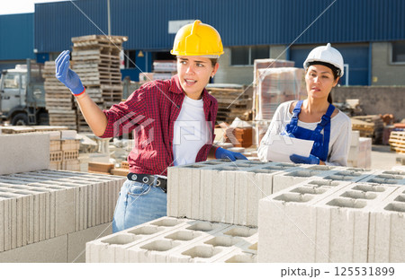 Female builders with hollow concrete blocks in outdoor warehouse Female builders with hollow concrete blocks in outdoor warehouse 125531899