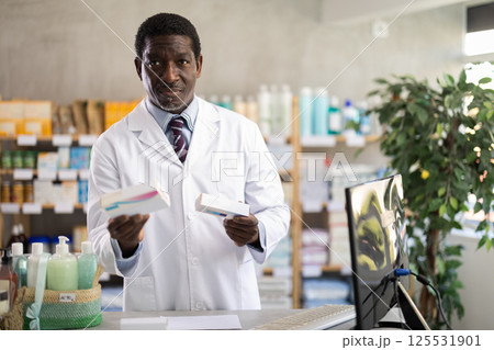 Adult man pharmacist offering pills box 125531901