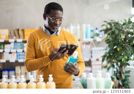 Man scanning mouthwash for ingredients and info in drugstore Man scanning mouthwash for ingredients and info in drugstore 125531903