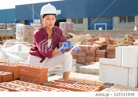 Woman with document in construction material storage Woman with document in construction material storage 125531930