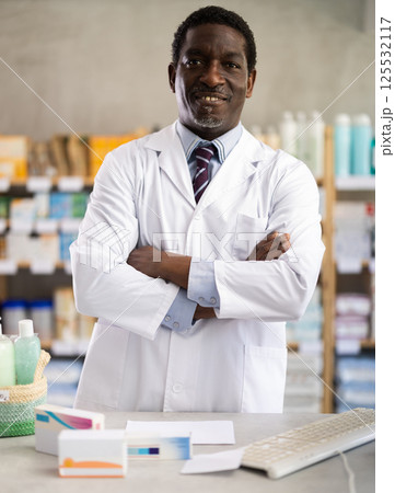 Confident African American pharmacist standing at pharmacy counter Confident African American pharmacist standing at pharmacy counter 125532117