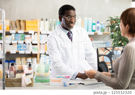 Pharmacist searches for medicine on computer for female buyer 125532320