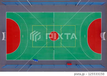 Aerial view of a vibrant basketball court with red and green markings in a sunny environment 125533150