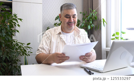 Man Reviewing Work Documents and Smiling 125533297