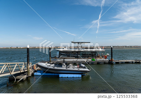 A tourist boat is moored at a pier with clear skies over the water. 125533368