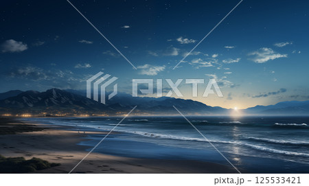 Starry night beach with mountains and city lights glowing under a rising sun on the distant horizon 125533421