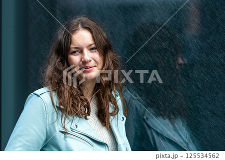 portrait of a young sensual brunette with long hair by a polished dark marble wall 125534562