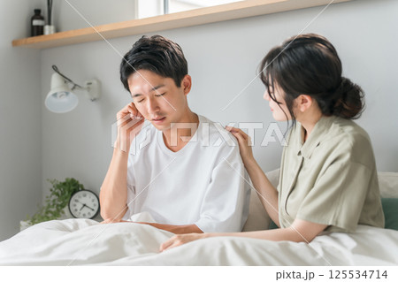 朝寝室で耳鳴り・難聴・外耳炎・中耳炎に悩む男性と心配する女性・夫婦・カップル 朝寝室で耳鳴り・難聴・外耳炎・中耳炎に悩む男性と心配する女性・夫婦・カップル 125534714