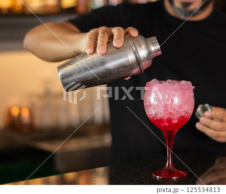 Bartender prepares preparing refreshing tequila sunrise drink - cocktail tequila sunrise with tequila, juice and grenadine syru 125534813
