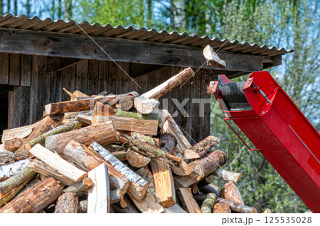 Pile of chopped firewoodin front of a wood chipper 125535028