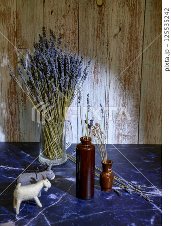 Felt toys of goats and donkeys, stems with lavender flowers in clay vases 125535242
