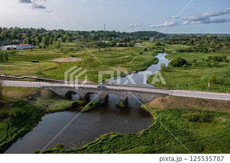 Stone Bridge Crossing River in Grassy Area Stone Bridge Crossing River in Grassy Area 125535787