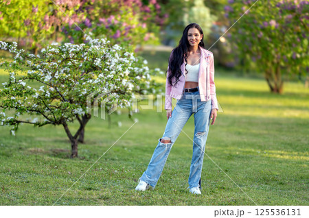 Woman in pink jacket standing in park. Shallow depth of feld Woman in pink jacket standing in park. Shallow depth of feld 125536131