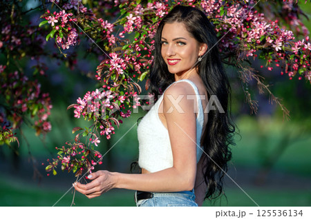 Woman posing near blooming tree in spring. Shallow depth of feld Woman posing near blooming tree in spring. Shallow depth of feld 125536134