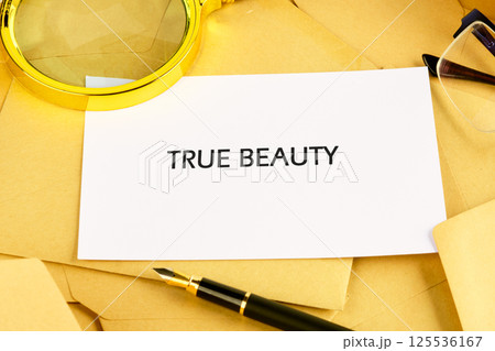A collection of envelopes and a pen are arranged on a surface, prominently featuring a card that reads True Beauty. The setup showcases a thoughtful exploration of beauty A collection of envelopes and a pen are arranged on a surface, prominently featuring a card that reads True Beauty. The setup showcases a thoughtful exploration of beauty 125536167