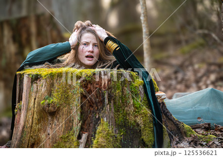 Woman trapped in tree stump in forest. Shallow depth of feld Woman trapped in tree stump in forest. Shallow depth of feld 125536621