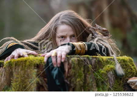 Woman in forest hiding behind tree stump. Shallow depth of feld Woman in forest hiding behind tree stump. Shallow depth of feld 125536622