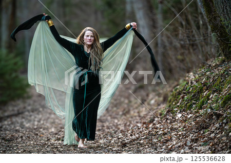 Woman dancing with veil in forest path. Shallow depth of feld 125536628