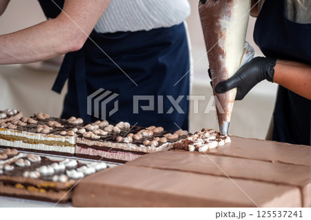 Baker decorating chocolate cake with piping bag. Shallow depth of feld Baker decorating chocolate cake with piping bag. Shallow depth of feld 125537241