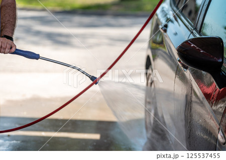 Closeup car washing with high pressure car washer spray gun 125537455