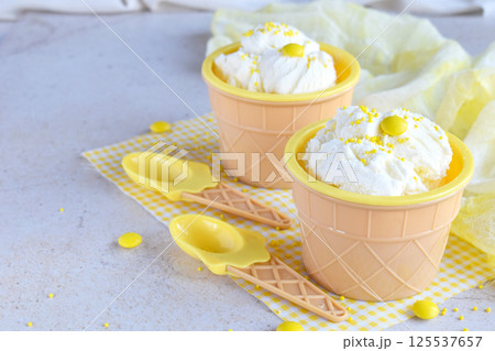 Three portions of vanilla ice cream with colorful candy decorations served in waffle cups with spring flowers on a bright background perfect for dessert menus summer promotions and sweet food concepts Three portions of vanilla ice cream with colorful candy decorations served in waffle cups with spring flowers on a bright background perfect for dessert menus summer promotions and sweet food concepts 125537657