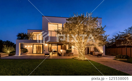 modern luxury house illuminated at night, featuring large tree adorned with thousands of warm white fairy lights, creating magical and inviting atmosphere 125538005