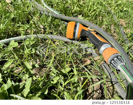 Garden Hose and Spray Nozzle on Grass for Watering 125538318