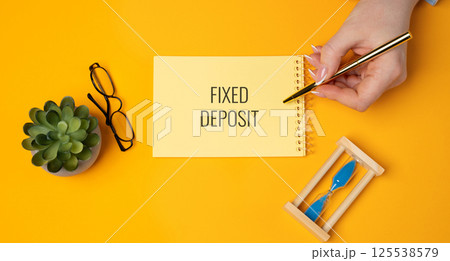 Fixed deposit concept. Financial product offered by banks and financial institutions where you deposit a lump sum of money for a fixed period of time at a fixed interest rate. A woman writes in notes Fixed deposit concept. Financial product offered by banks and financial institutions where you deposit a lump sum of money for a fixed period of time at a fixed interest rate. A woman writes in notes 125538579