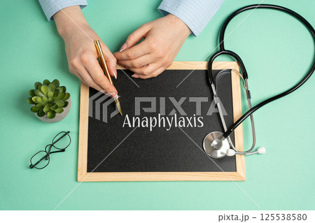 Anaphylaxis concept. Serious, potentially fatal allergic reaction and medical emergency that is rapid in onset and requires immediate medical attention. Woman writes on the board near the stethoscope Anaphylaxis concept. Serious, potentially fatal allergic reaction and medical emergency that is rapid in onset and requires immediate medical attention. Woman writes on the board near the stethoscope 125538580