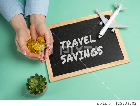 Travel savings concept. Money you intentionally set aside to fund your future trips or vacations. Board with an inscription near the plane and coins in female hands 125538582