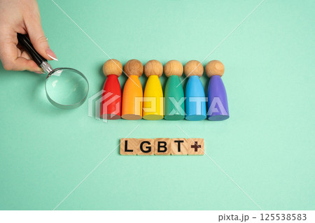 Hand with magnifying glass chooses figures of people among LGBT representatives. Find yourself in the list of sexual orientations. Self-identification, exploring sexual orientations. Wooden blocks 125538583