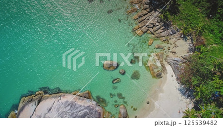 This breathtaking coastal landscape highlights crystal-clear turquoise waters lapping against a sandy beach bordered by lush greenery. Rocky formations create a unique shoreline. This breathtaking coastal landscape highlights crystal-clear turquoise waters lapping against a sandy beach bordered by lush greenery. Rocky formations create a unique shoreline. 125539482