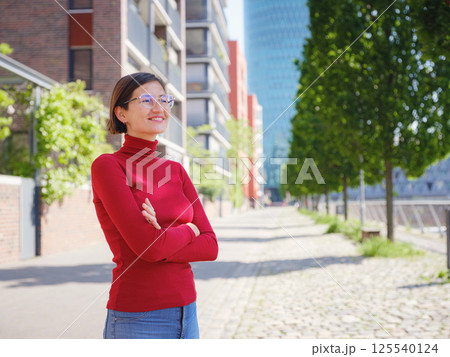 Woman in glasses stands in center of Frankfurt, 125540124