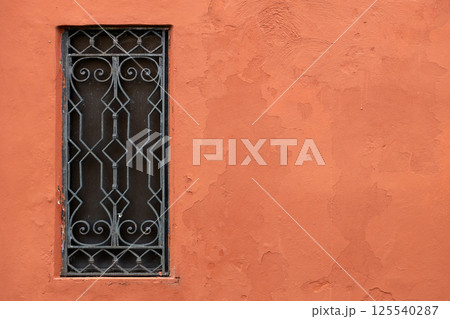Decorative iron window on terracotta wall 125540287
