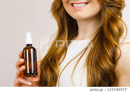 Woman applying hair cosmetic Woman applying hair cosmetic 125540557