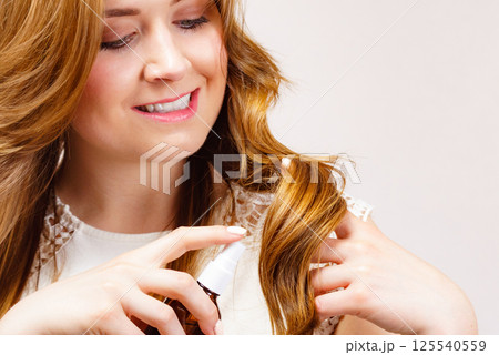Woman applying hair cosmetic Woman applying hair cosmetic 125540559