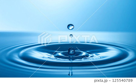 serene water surface captures beauty of water droplet impacting, creating ripples and reflections in tranquil blue environment. scene evokes sense of calm and clarity 125540789