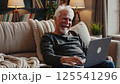 Elderly man enjoying digital device laptop entertainment home comfort retirement lifestyle modern technology senior learning relaxed atmosphere cozy living room evening leisure 125541296