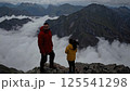 Two adventurers standing on mountain peak above clouds dramatic moody atmosphere achievement hiking expedition success teamwork exploration wilderness adventure outdoor lifestyle 125541298
