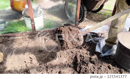 A farmer works on the land. Shoveling the earth in the greenhouse. Agricultural Labor Farmer Foot and Shovel in the Rural Field. man working on the ground 125541377