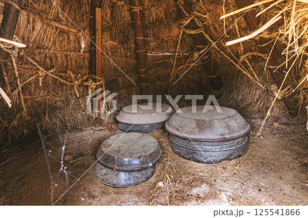 Traditional Korean straw hut with large clay pots inside used for fermenting and producing kimchi traditional food Traditional Korean straw hut with large clay pots inside used for fermenting and producing kimchi traditional food 125541866