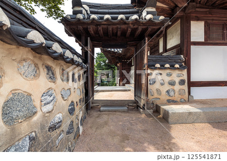 Traditional Korean hanok entrance gate with stone walls plastered with exposed stones and wooden tiled roof in a historic village setting Traditional Korean hanok entrance gate with stone walls plastered with exposed stones and wooden tiled roof in a historic village setting 125541871