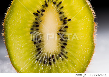 The kiwi piece stands out brightly against the solid background. The green kiwi is shown in detail, highlighting its juiciness. 125542683