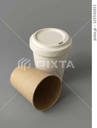 New beige kraft paper cups and reusable bamboo coffee cup with a lid on a gray closeup, mockup New beige kraft paper cups and reusable bamboo coffee cup with a lid on a gray closeup, mockup 125542851