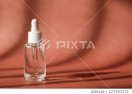Serum cosmetic bottle, hyaluronic acid on brown background. Serum product cosmetic with peptide and collagen, modern brand glass cosmetics packaging. Cosmetic showcase Serum cosmetic bottle, hyaluronic acid on brown background. Serum product cosmetic with peptide and collagen, modern brand glass cosmetics packaging. Cosmetic showcase 125543172