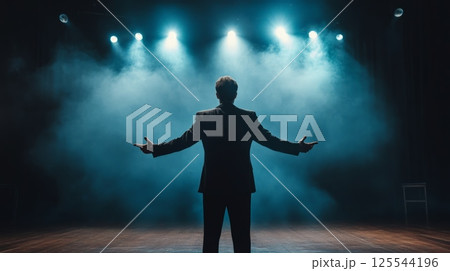 Back view of a singer performing on stage with arms wide open, embracing the audience under blue spotlights and smoke, creating a dramatic and captivating atmosphere 125544196