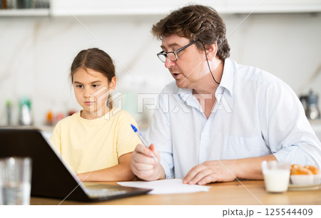 Little daughter shows her father how to use laptop 125544409