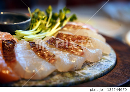 A beautifully arranged plate of fresh sashimi with garnishes. 125544670