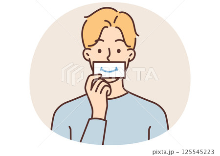 Man puts piece paper with image of smile to mouth, wanting to fake positive emotions during stress Man puts piece paper with image of smile to mouth, wanting to fake positive emotions during stress 125545223