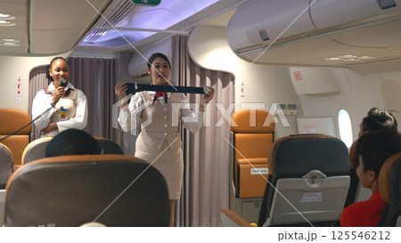 Asian stewardess safety explaining passengers how to use seat belt fastening in airplane, air hostess uniform safety demonstration presenting a seat belt, aircraft safety 125546212